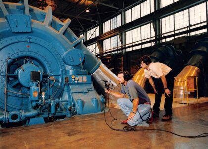 Photo is engineers Michael Bishop and Scott Burgess posed in front of a large power turbine