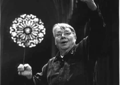 Conductor Robert Shaw in front of a church window.